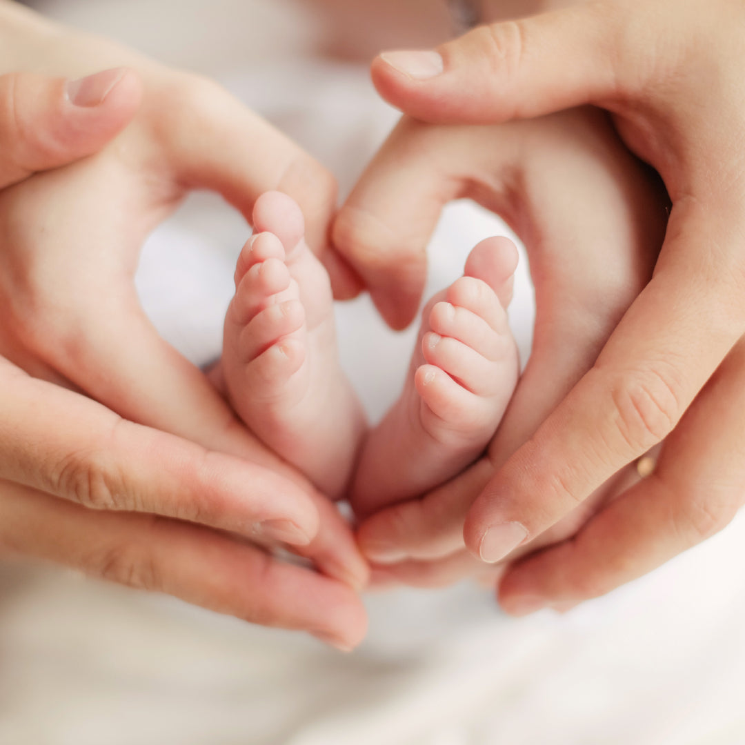 Heart hands around a newborn baby's feet