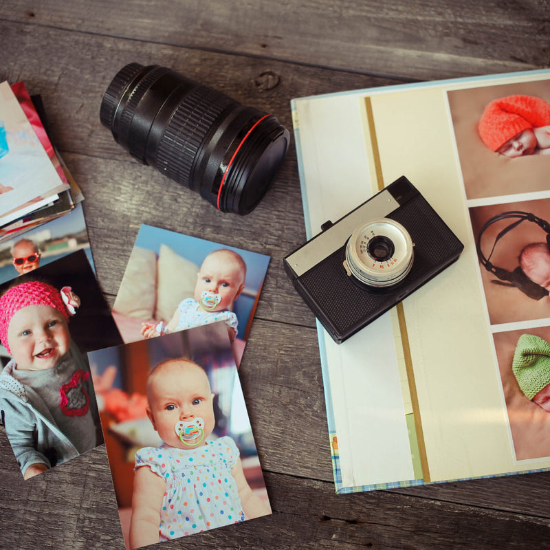 Baby photos, album and retro camera on a wooden table