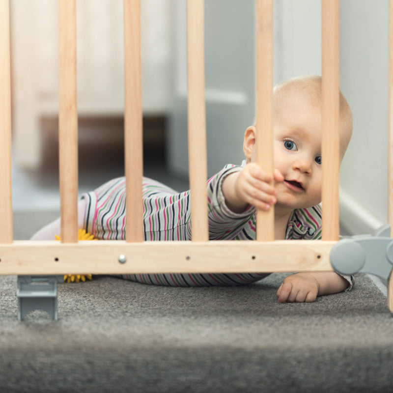Baby playing with a gate at the top of the stairs