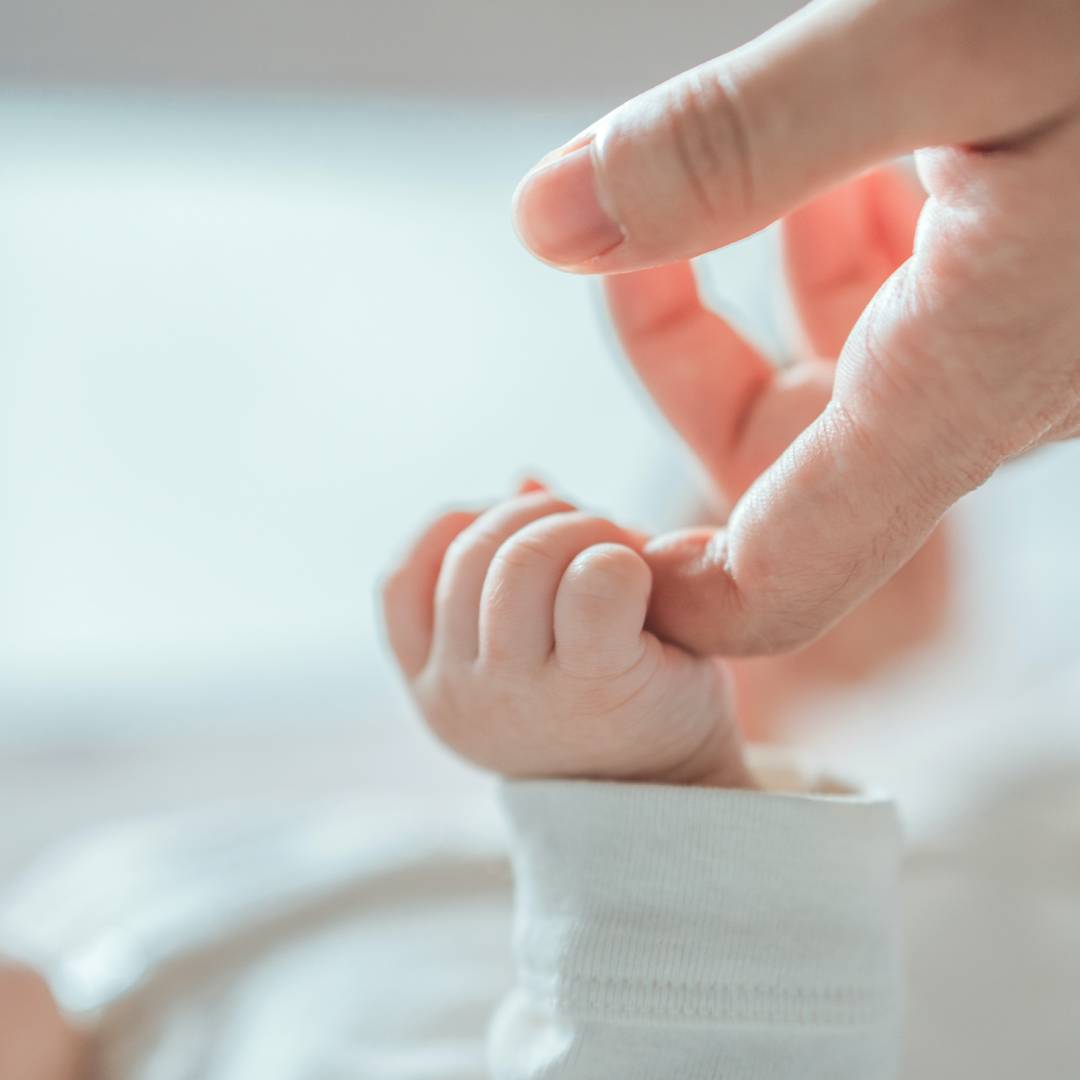 Newborn baby holding parent's finger