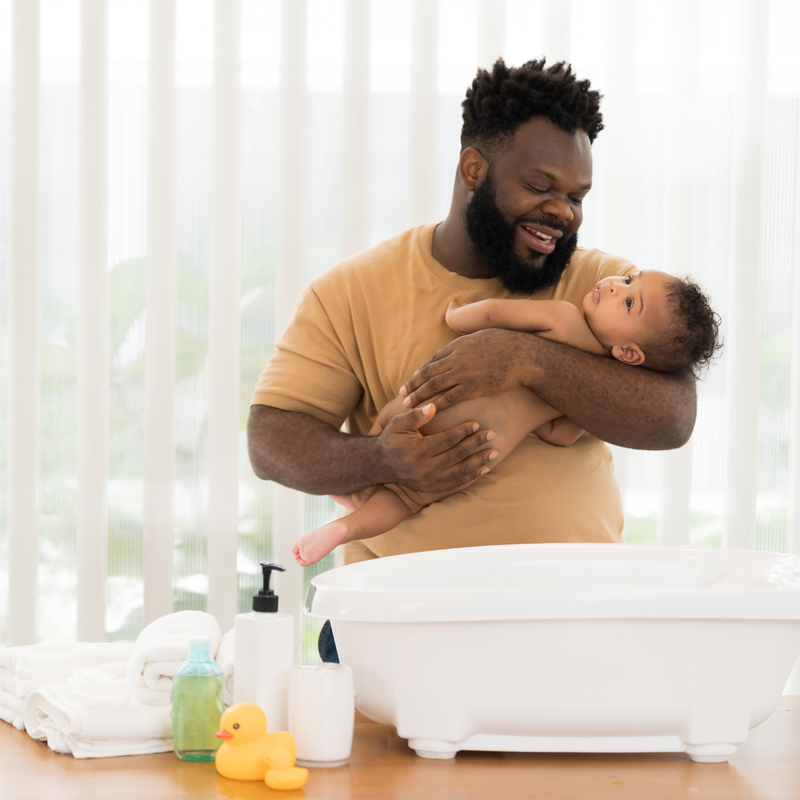 A dad smiling as he prepares to bathe his baby