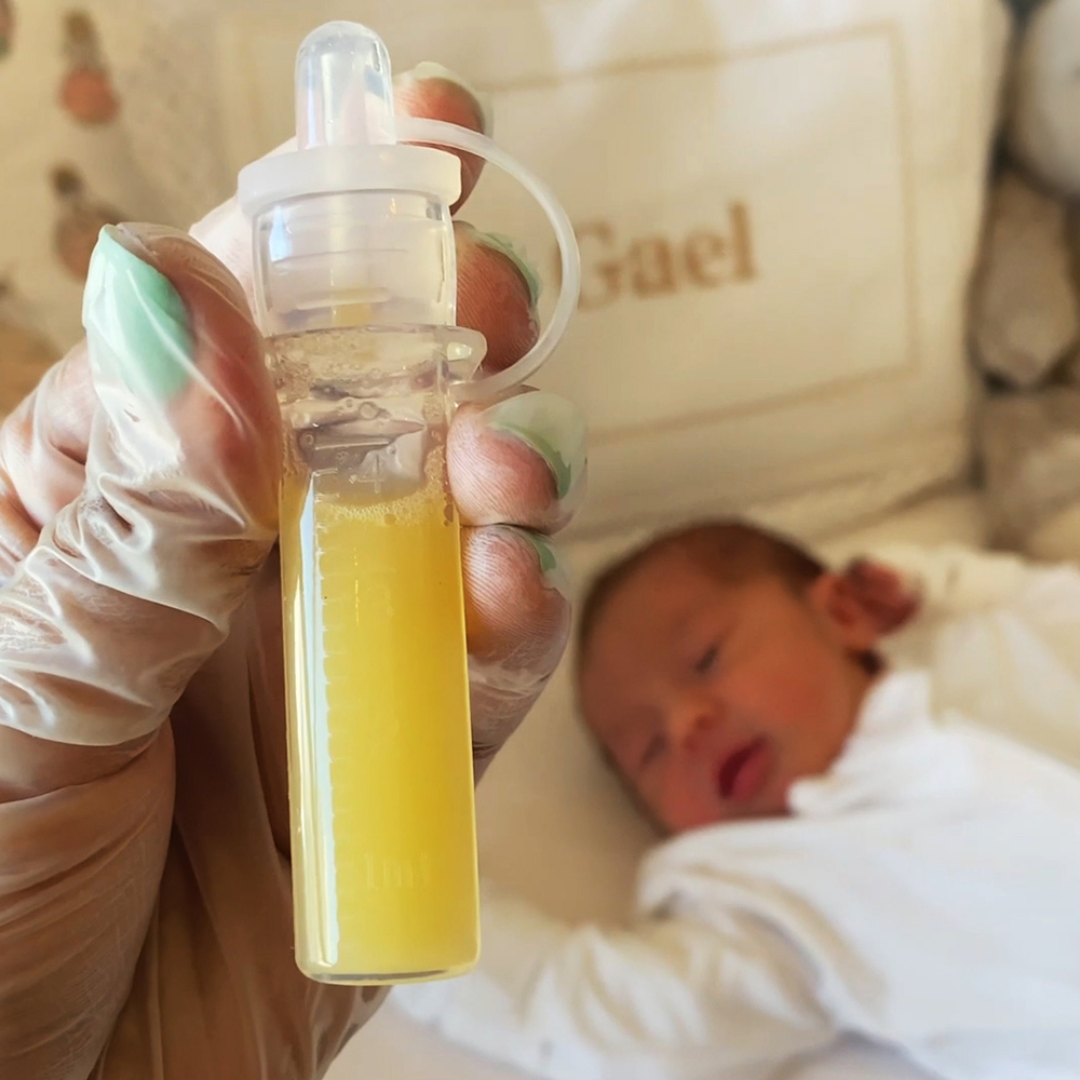 Freshly expressed colostrum in a Haakaa Silicone Colostrum Collector. Baby sleeps in the background.