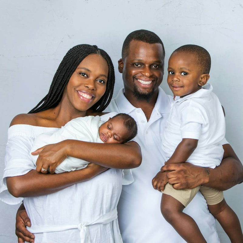 Smiling parents holding their newborn and toddler