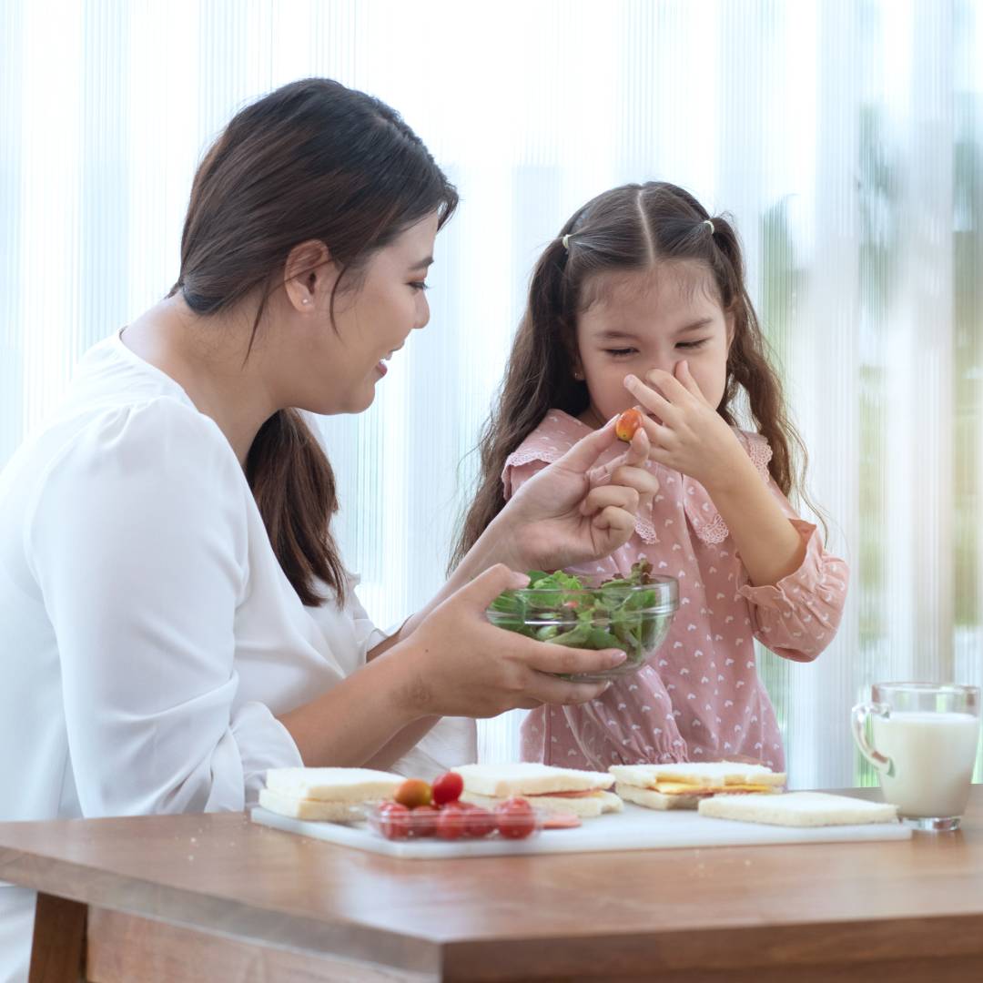 Child covers her face when mother offers her vegetables