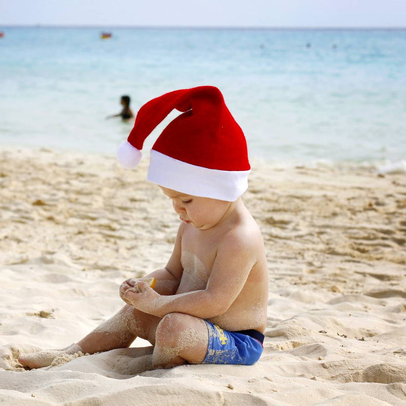 Baby sitting on the beach wearing a Santa hat - summer Christmas